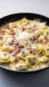 Delicious creamy tortellini carbonara dish garnished with herbs